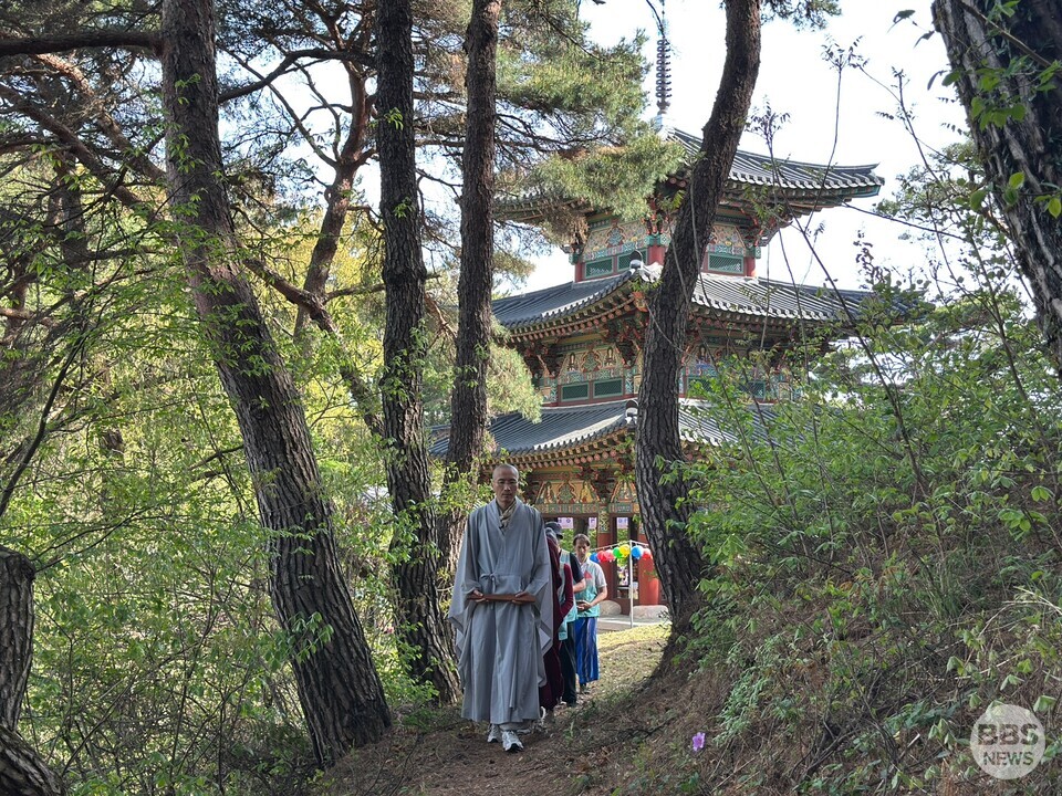 나주 미륵사 미륵전을 배경으로 숲길을 걷고 있는 혜원스님과 유럽인 템플스테이 참가자들.
